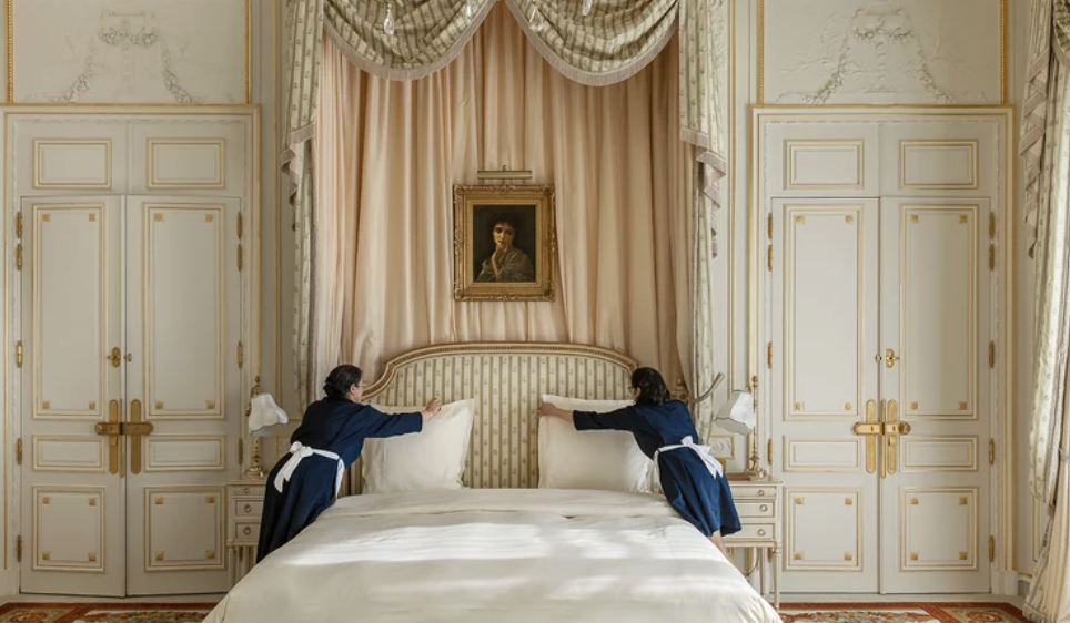 The image shows a luxurious bedroom suite at the Ritz Paris hotel. 